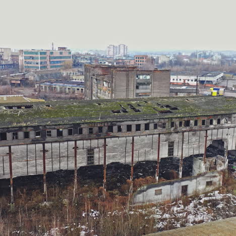 almost destroyed building with holey roof in the city. top view of ruined industrial building and some cars on a road. aerial view