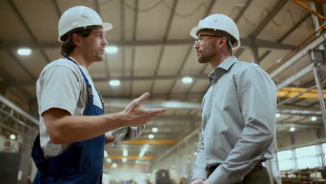 ingeniero y trabajador industrial estrechando la mano y hablando en la fábrica