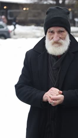 a bearded man in a black coat stands alone in a snowy landscape a bearded man in a black coat and hat stands alone in a snowy landscape reflecting as snowflakes fall around him symbolizing solitude
