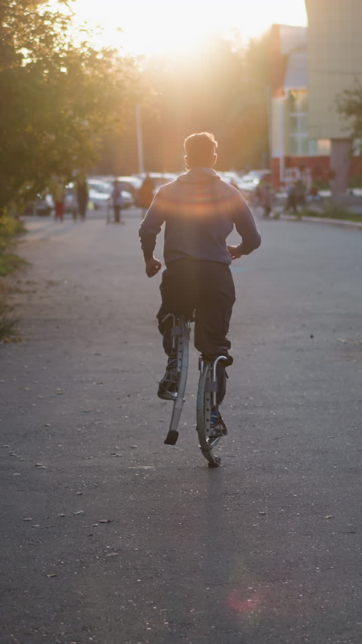 hombre corriendo en pilotes a lo largo de una calle residencial tranquila durante la puesta de sol, capturado por detrás. está vestido con suéter y pantalones oscuros, con la cálida luz del sol destacando la escena al aire libre tranquila