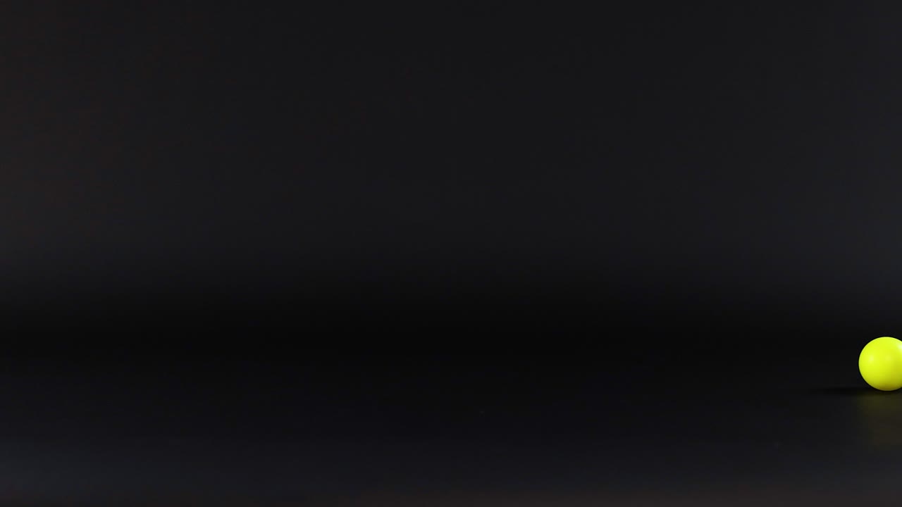 una pelota de ping pong rodando a través de una superficie oscura