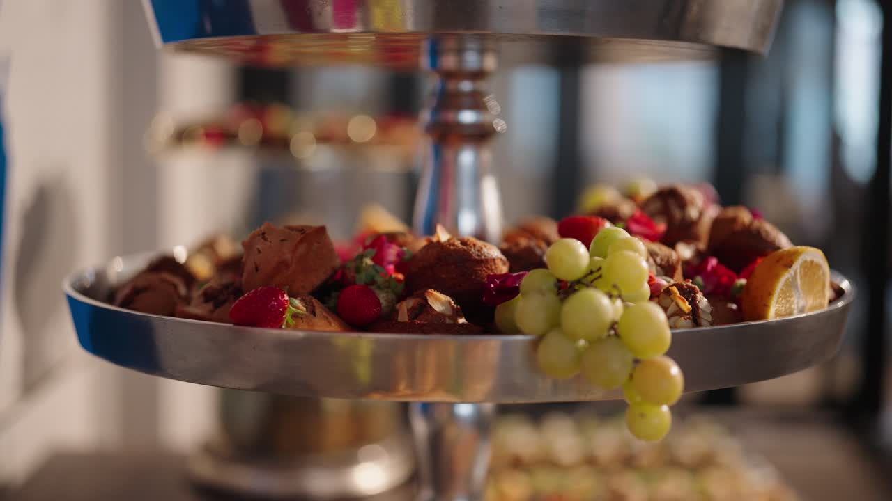 A display of fruits and muffins on a metal tiered serving tray showing a varied array of healthy foods