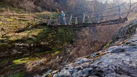 resolute man crosses risky wooden river trail footbridge to take photograph