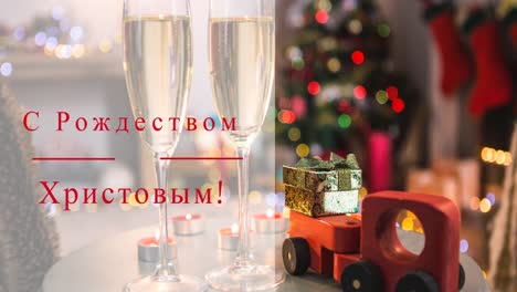 Animation-of-christmas-greetings-in-russian-over-champagne-glasses-and-christmas-tree