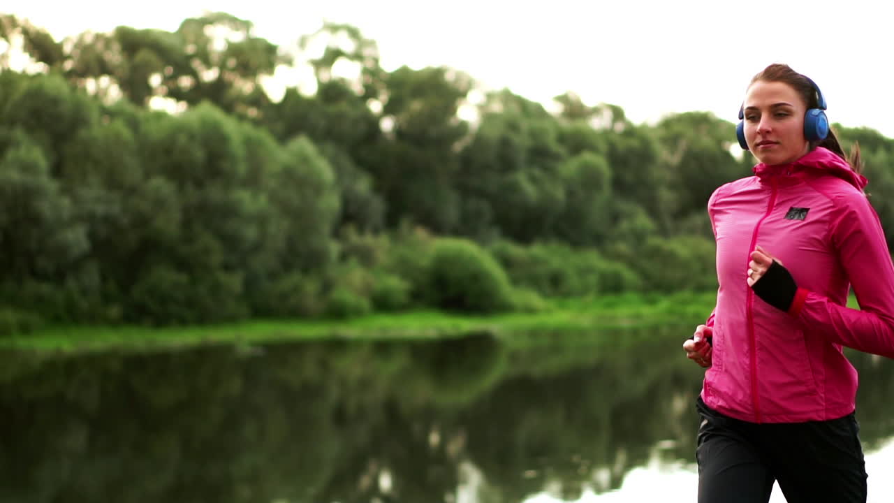 una carrera matutina en el parque cerca del estanque en los rayos soleados del amanecer, la niña se está preparando para mariano y llevar un estilo de vida saludable
