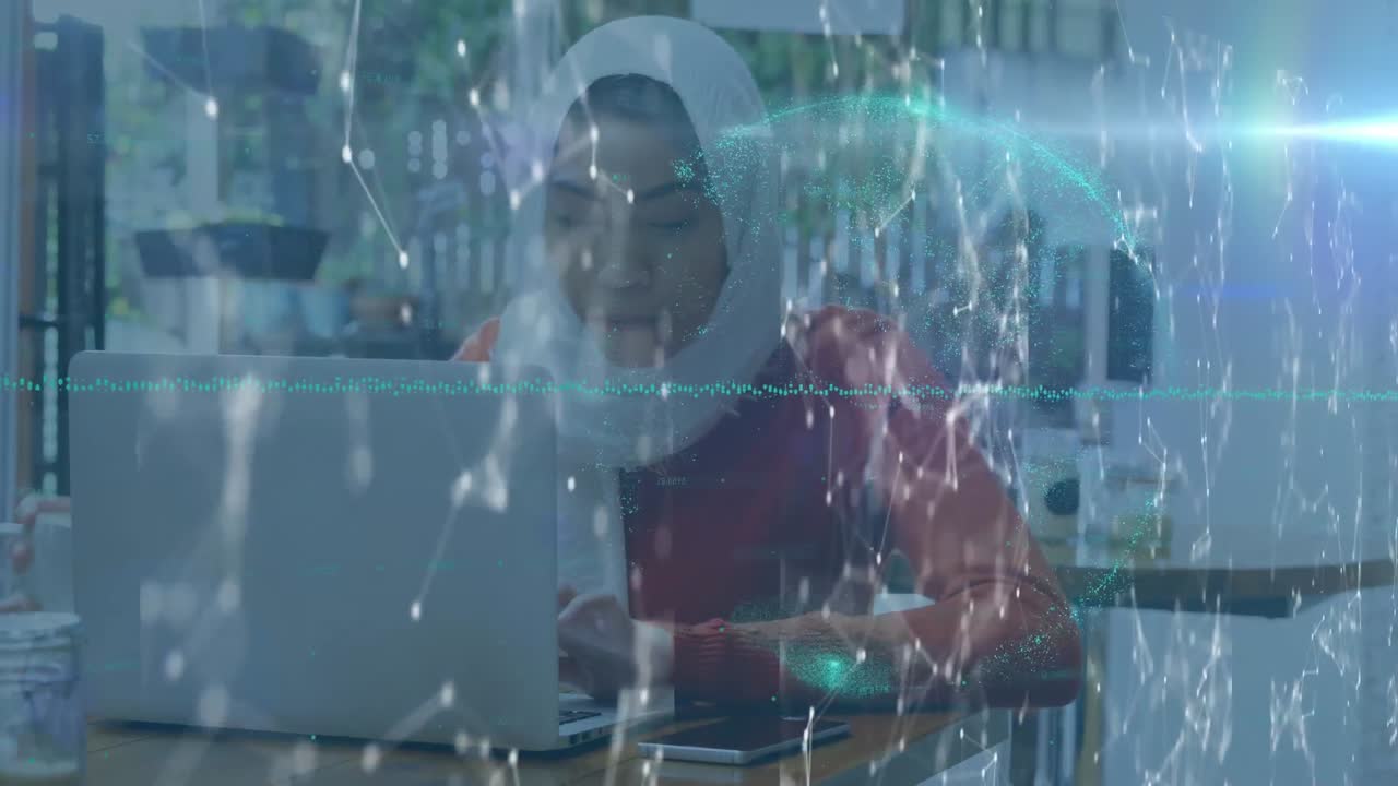 Globe of network of connections against woman in hijab drinking coffee while using laptop