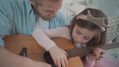Little-Daughter-Dressed-As-A-Princess-Plays-Guitar-With-Her-Daddy-At-Home