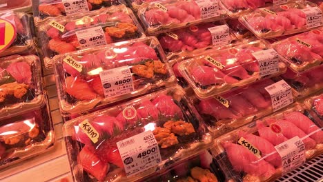 various sushi packs on a supermarket shelf.