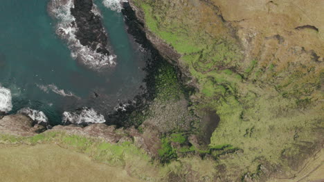 Bird's-eye-rotating-shot-above-cliff-cave,-Grimsey-Island-in-Arctic-Circle