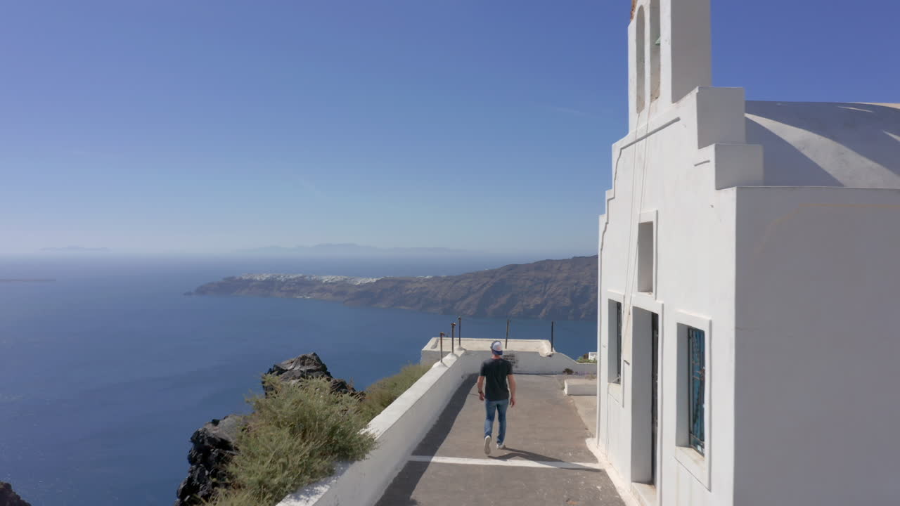 antena: un hombre camina junto a una iglesia en santorini, grecia en un día soleado