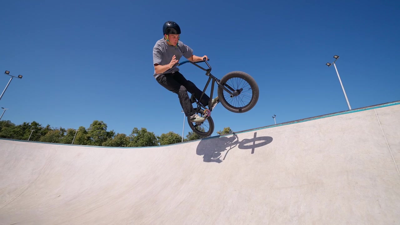 Giovane uomo in BMX che esegue un trick manuale nello skatepark