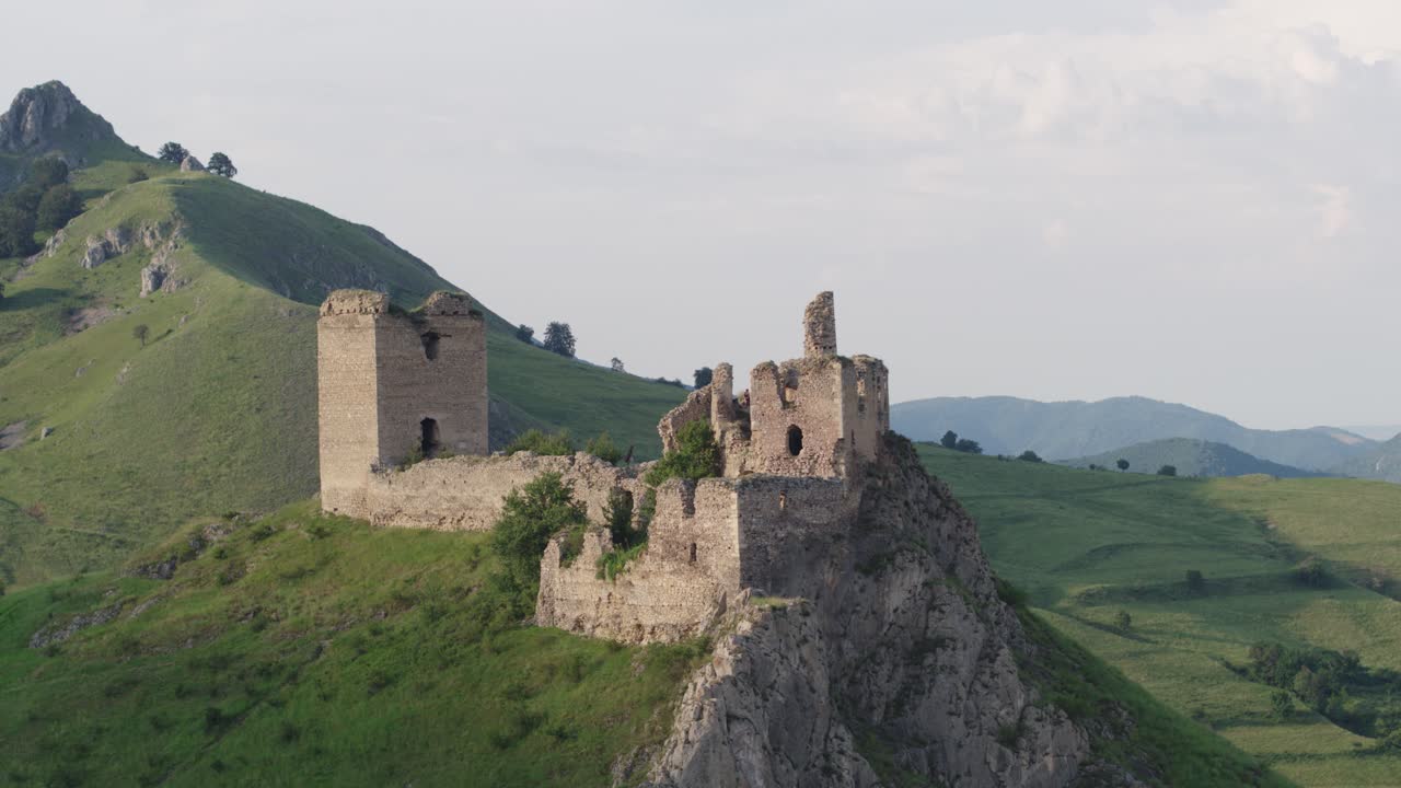Cinematic drone shot slowly ascending to reveal the medieval Trascău Fortress ruins in Colțești, Romania. An epic historical landmark in the mountains of Transylvania