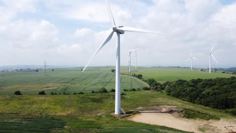 wind turbine rotating in field on cloudy hot summer day