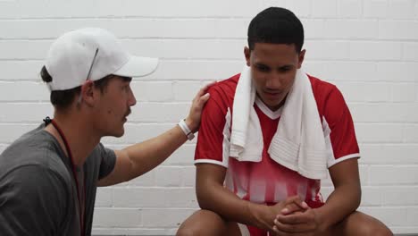 Race male rugby player listening his coach in the changing room