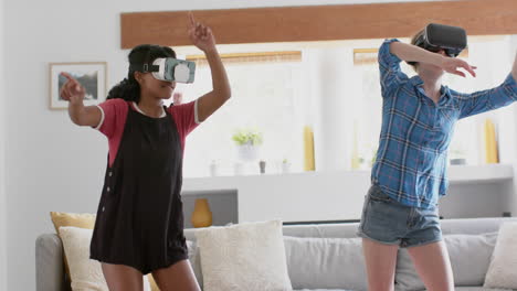 amigas adolescentes felices y diversas jugando y usando auriculares vr en casa, en cámara lenta