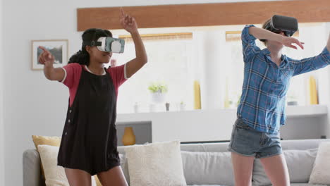 happy diverse teenage female friends playing and wearing vr headsets at home, slow motion