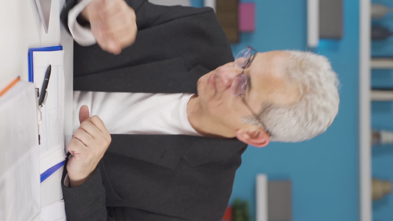 홈 오피스 직원의 수직 비디오는 그가 읽고 보는 것과 함께 그의 정신을 높입니다.