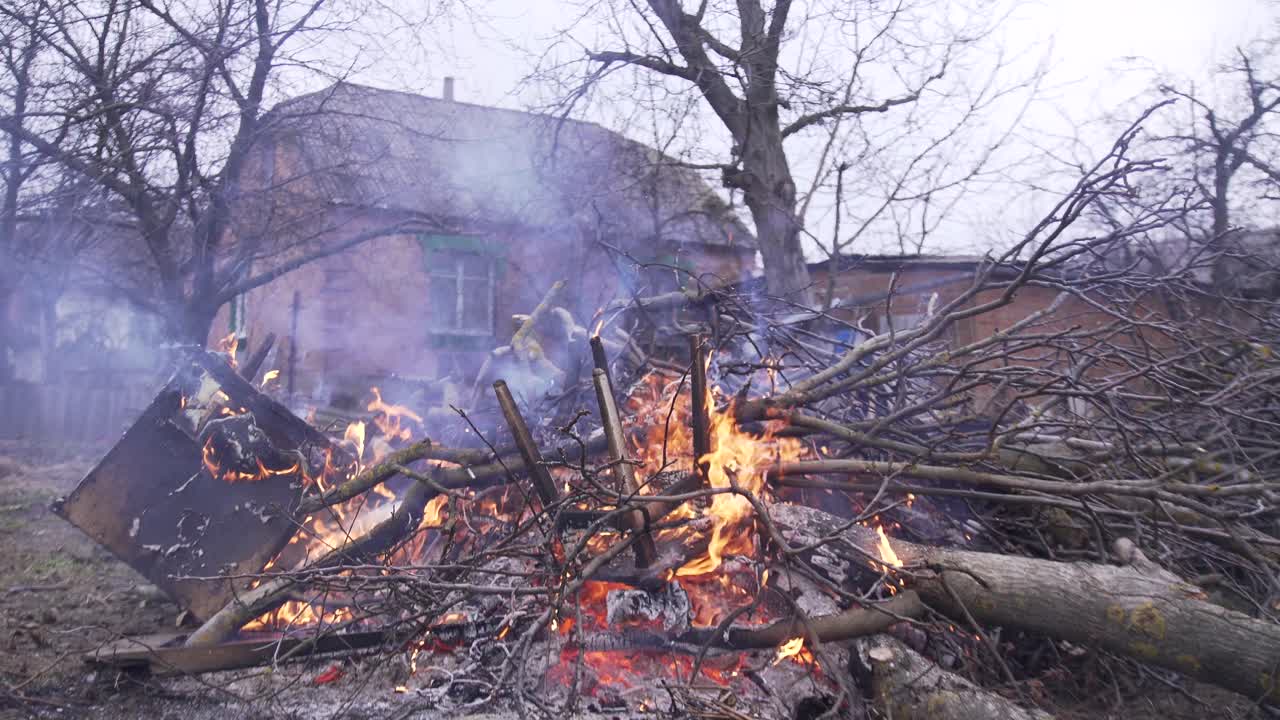 Bonfire of burning branches and wood with smoke in a rural setting