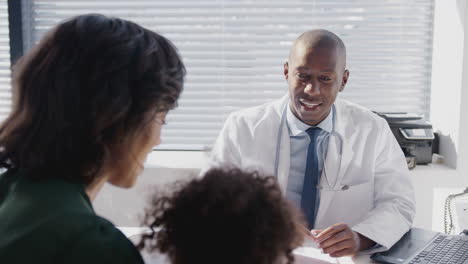 mother and daughter in consultation with doctor in office who gives child high five