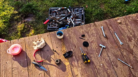 Scattered repair tools on wooden porch beside grassy yard