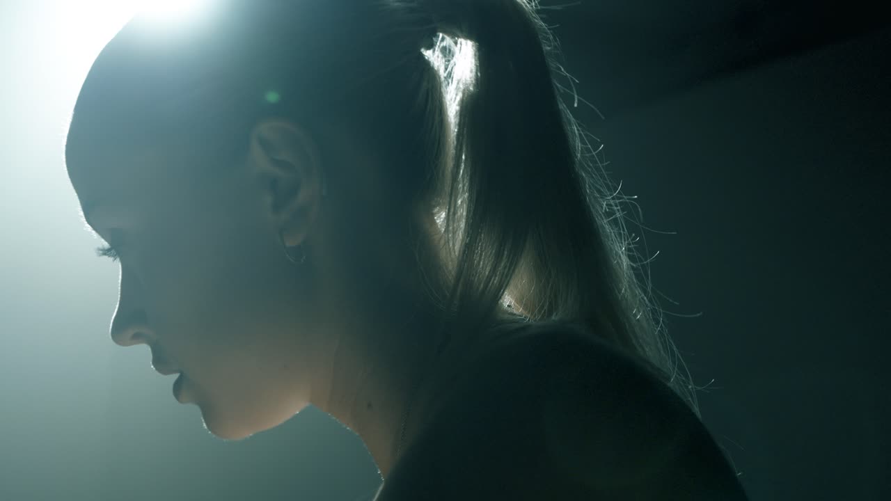 Back view closeup of a woman cycling, camera moving upward from her glutes to her hair as she flips it from left to right. The shot transitions through profile to a frontal view of her focused face