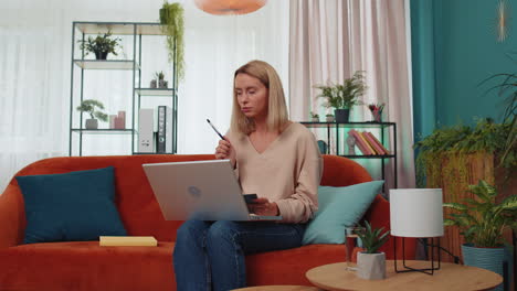 Girl-student-study-at-home-couch-on-laptop-computer-making-conference-video-call-talking-to-webcam