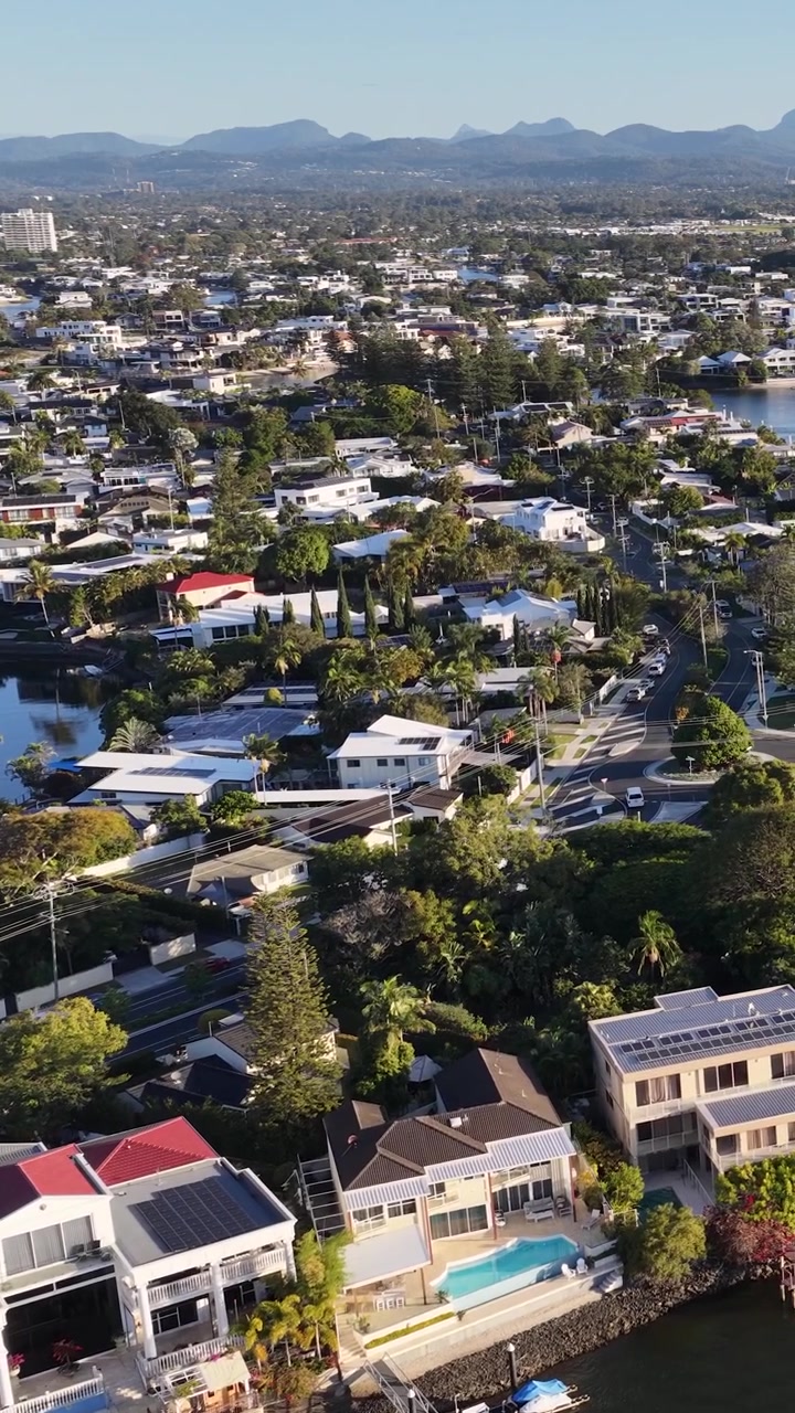 Toma de dron en picada paneando sobre lujosas casas frente al mar y canales suburbanos bajo la luz del día.