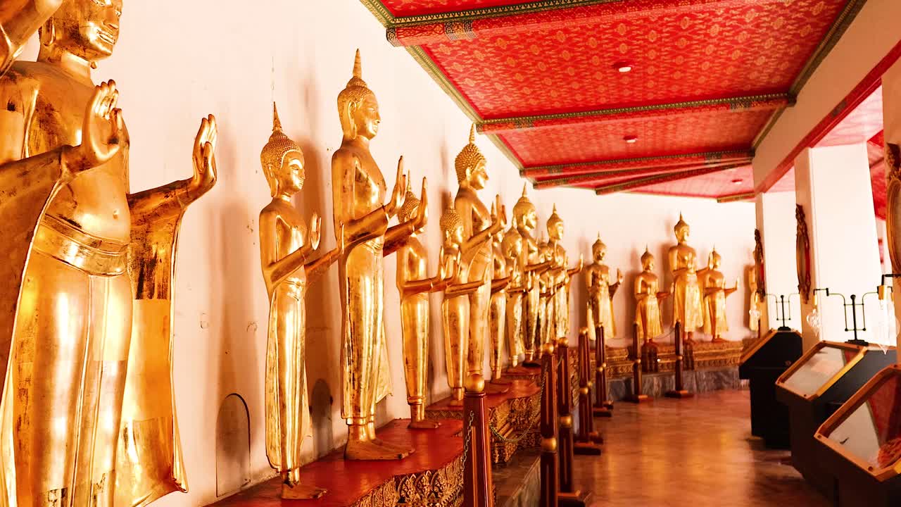 una fila de estatuas de buda de oro en wat pho