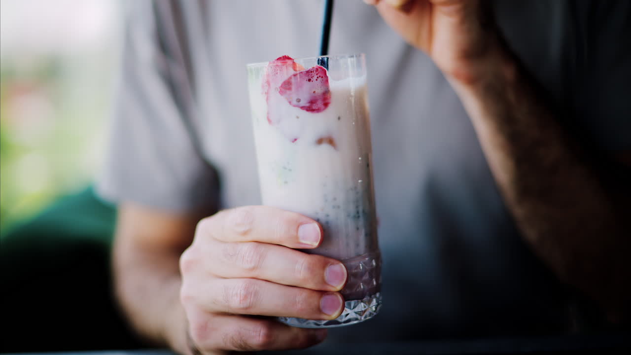 Man mixing a strawberry drink with a black straw at a restaurant