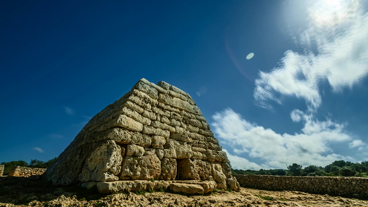 Nuvole bianche fluttuano in un cielo blu sopra la tomba megalitica sull'isola di Minorca