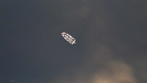 man standing on the boat catching fish in the lake by fishing rod