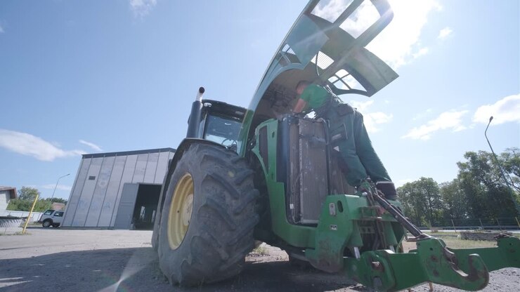 Farmer mechanic repairing tractor. Open tractor hood, engine. Repair agricultural technology