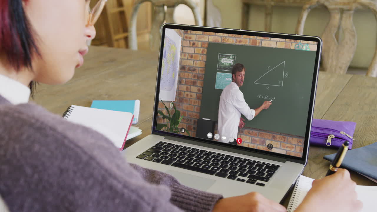 estudiante asiática usando una computadora portátil para una lección en línea con un profesor caucásico en la pantalla
