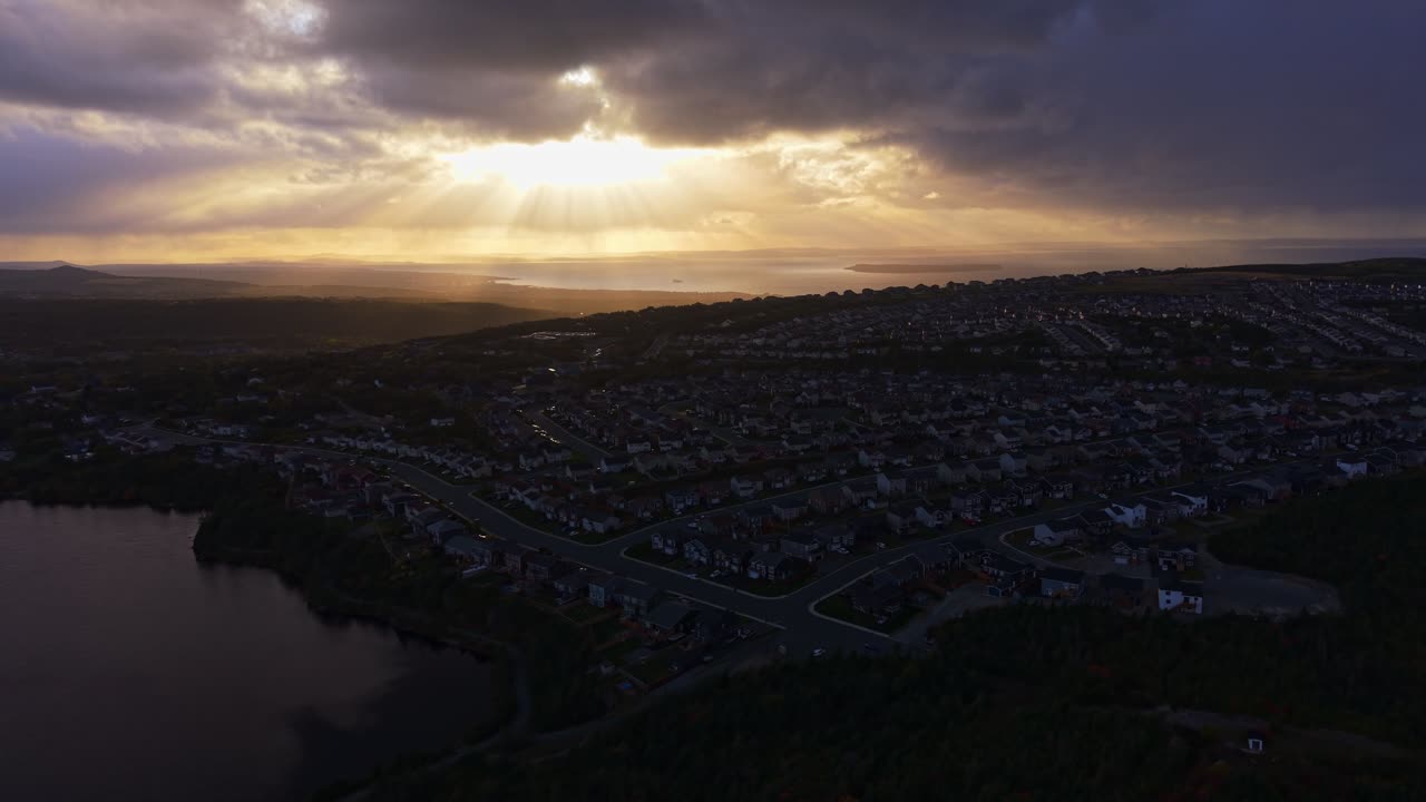 Striking aerial footage of Conception Bay, Newfoundland, capturing god rays breaking through clouds and casting light over open water. Dark sea contrasts with luminous sky in an awe-inspiring scene