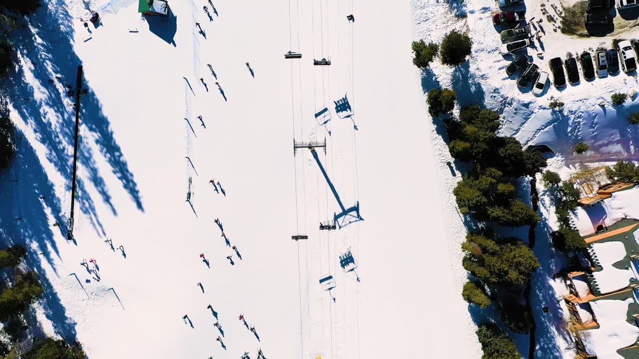 deportes de invierno, pista de esquí ocupada con personas montando el elevador junto al estacionamiento completo y el sendero lleno de gente