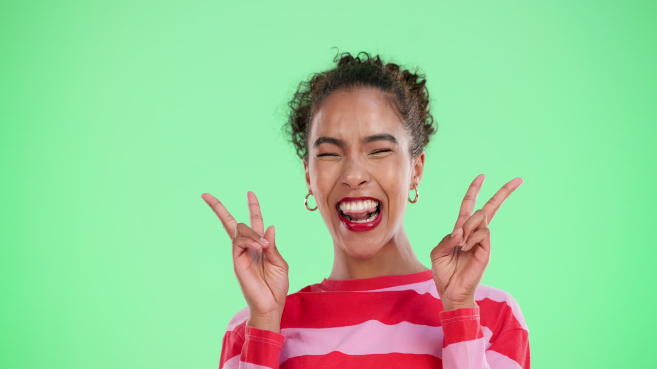A woman with curly hair smiles against a green screen