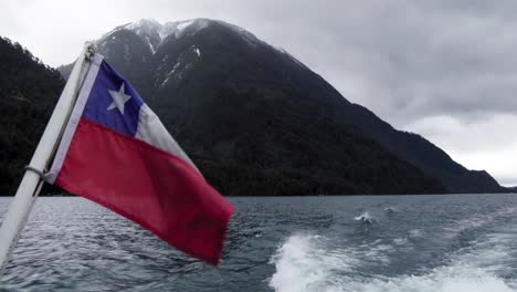 chilean flag waving with the lake of all saints and snow-capped mountains in the background