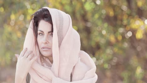 A-beautiful-brunette-model-poses-with-a-light-scarf-on-her-head-outdoors