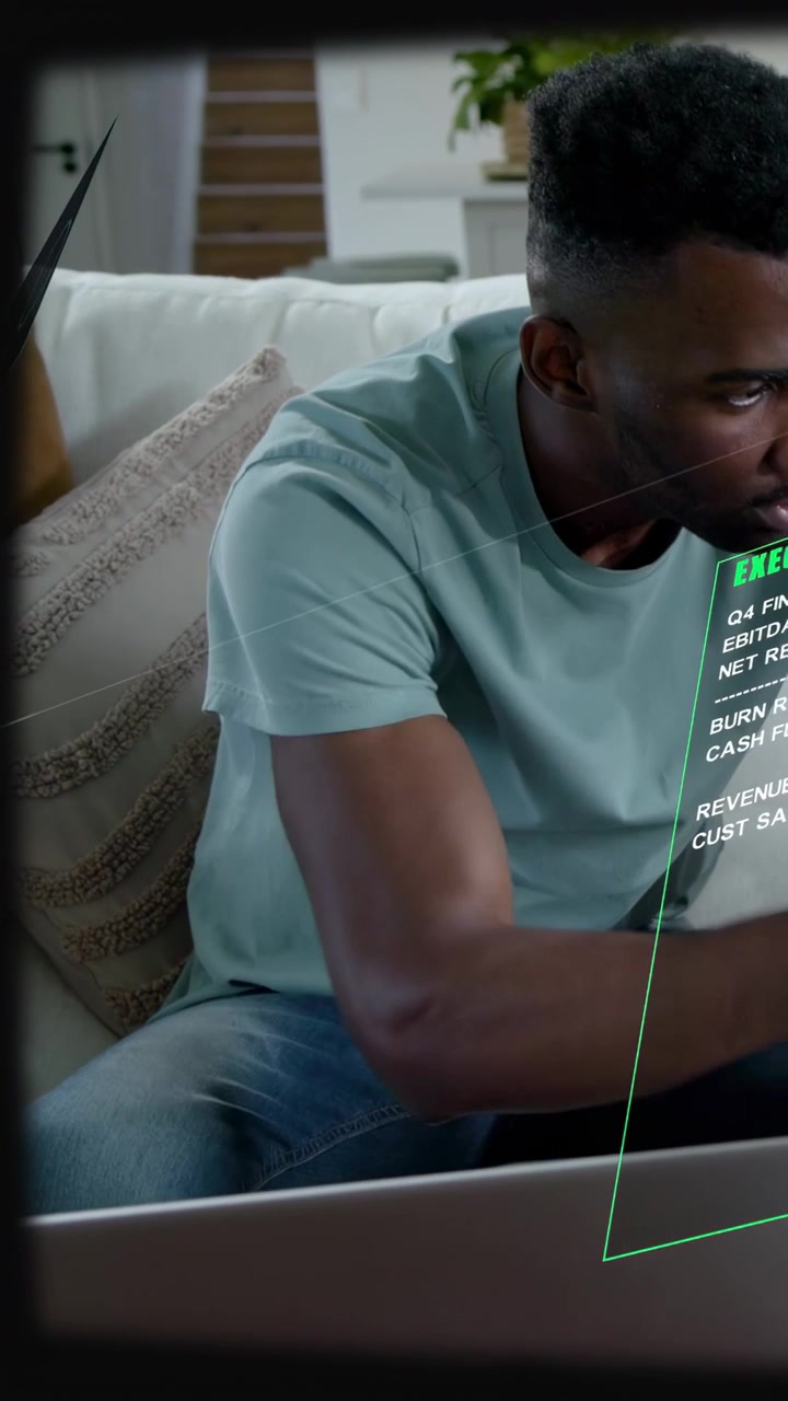 Vertical video: Man typing on couch and reading translucent HUD to check finance charts and metrics