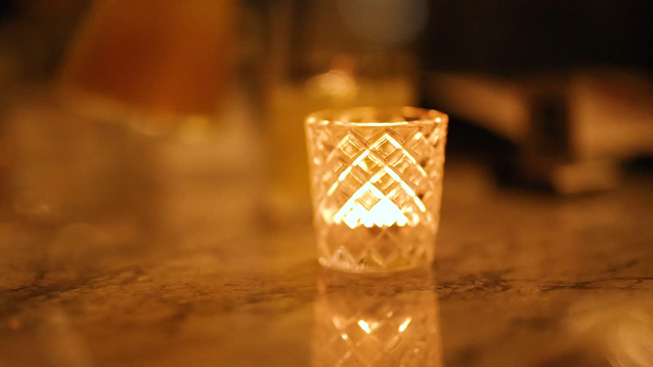 A candle flickers warmly on a marble surface, creating a cozy atmosphere with soft, ambient lighting