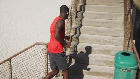 african american man running up the stairs, exercising outdoors by the seaside