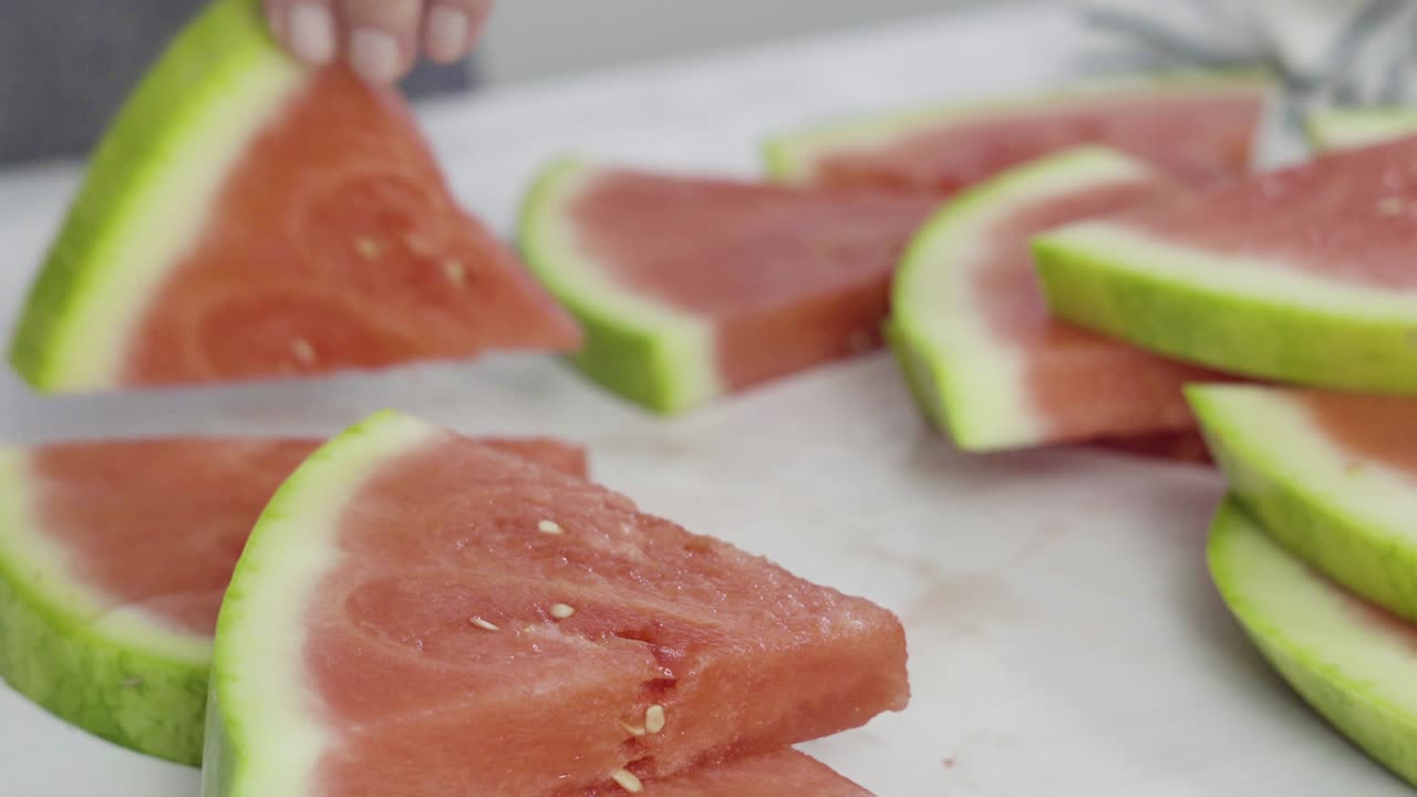 sandía roja sin semillas en una tabla de cortar blanca.