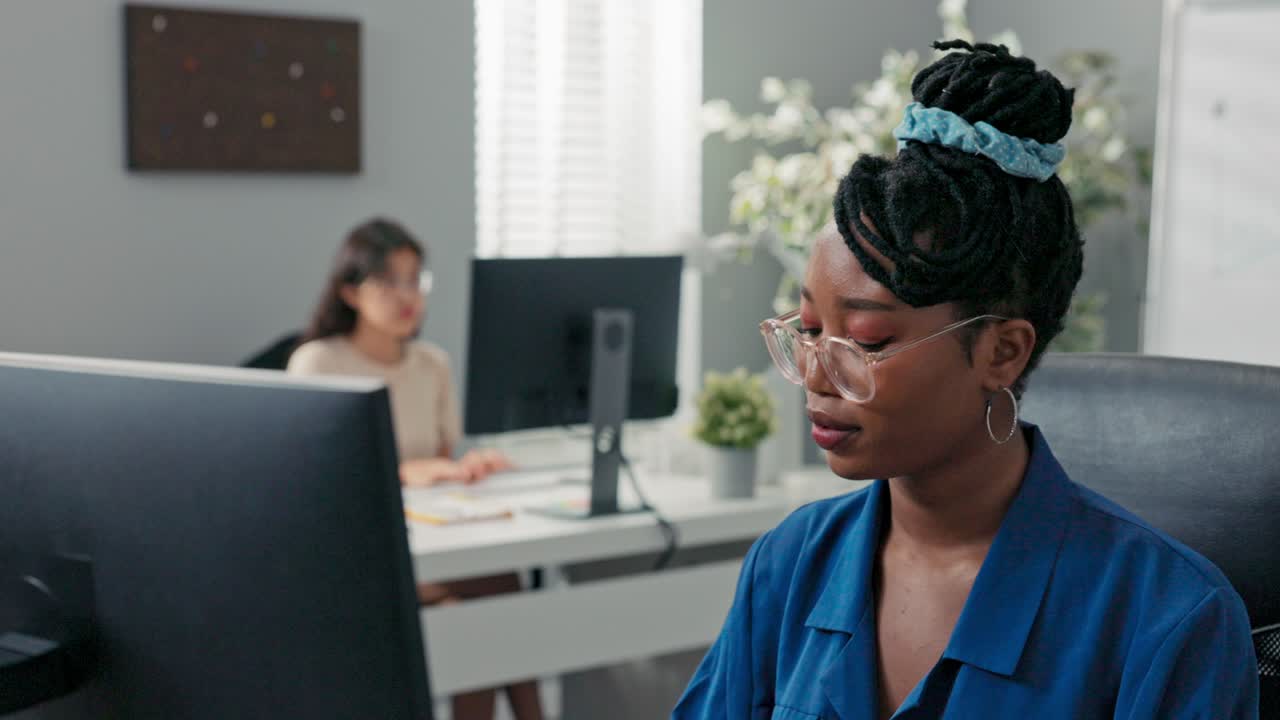 Polite, elegant customer service representative in large corporation sits at computer, tapping fingers on keyboard, surfing Internet, preparing documentation, filling out reports, making appointments