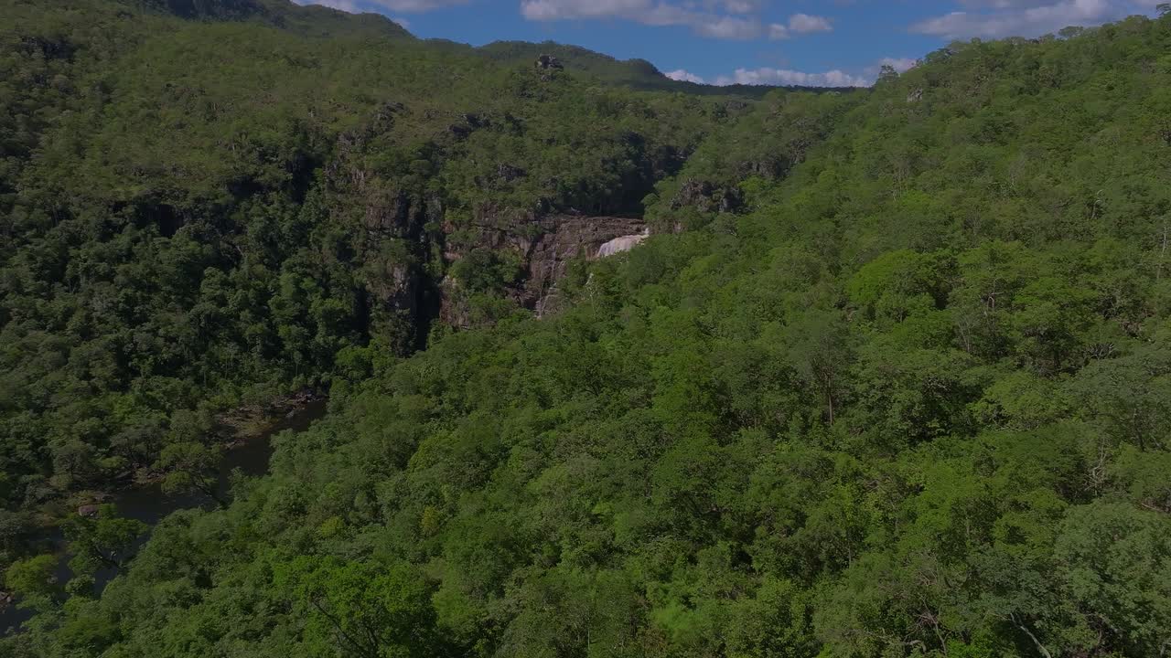 Cachoeira dos Saltos waterfall cascading through the lush vegetation of Chapada dos Veadeiros National Park in Goiás, Brazil, creating a stunning natural spectacle, drone reveal shot