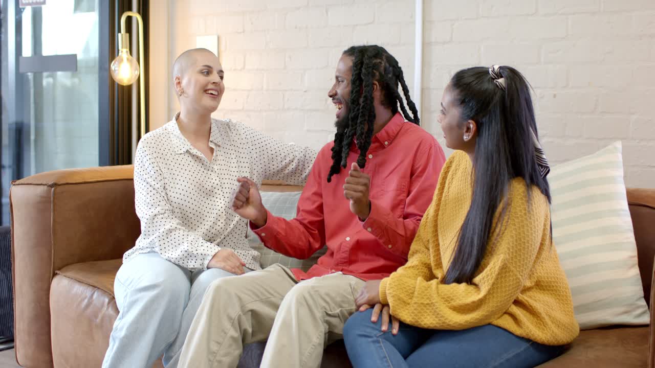 Forskellige venner smiler og udveksler livlige samtaler og deler latter på en lædersofa i en lounge