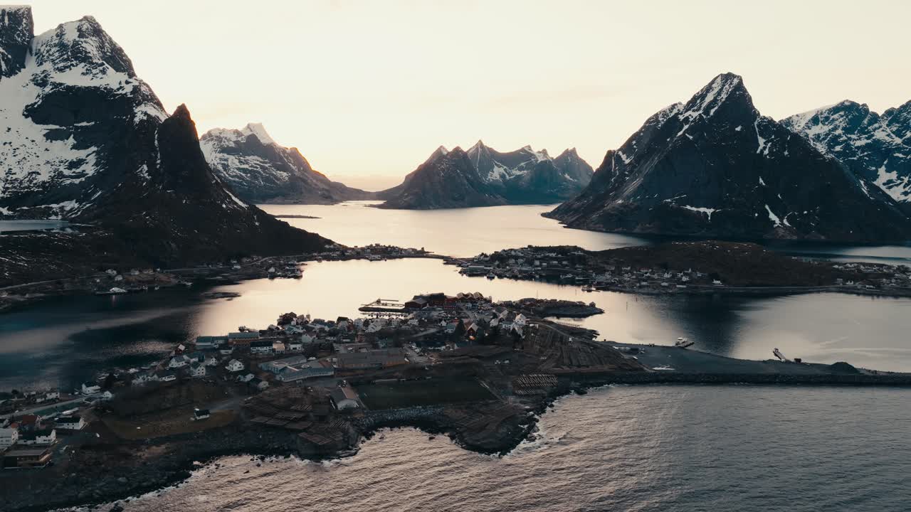 Reine, Lofoten Islands, Nordland, Norway - The Village Unfolds Across Narrow Peninsulas, Surrounded by Fjords and Sharp, Snow-draped Peaks at Sunrise - Aerial Drone Shot