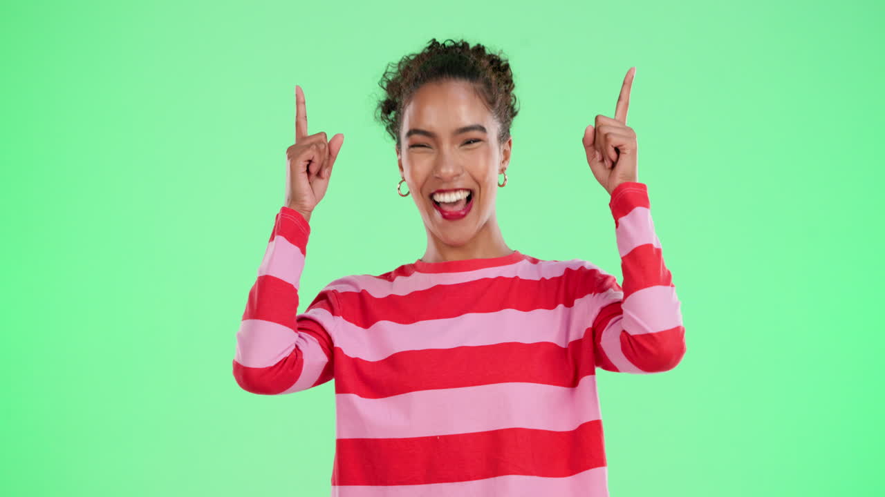 Happy woman pointing up against green background