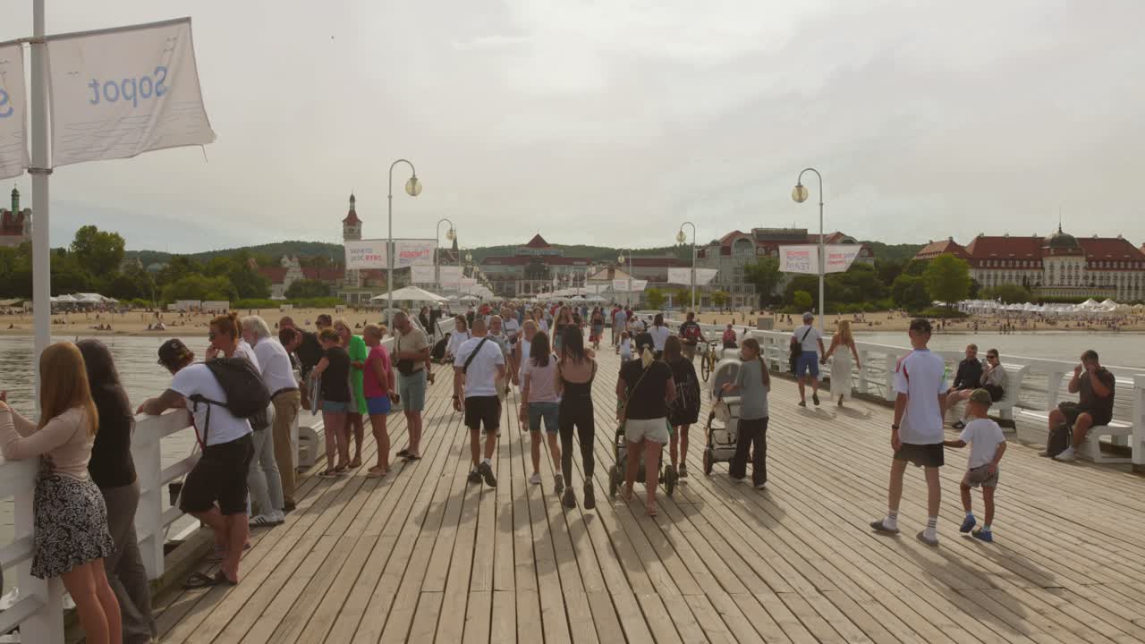 Visitors gather at Sopot pier, engaging in various activities while soaking in the vibrant atmosphere and breathtaking coastal views. The pier bustles with life.