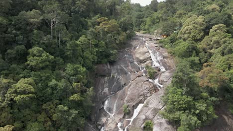 aerial: parte superior de la cascada de air terjun en la cara del acantilado de granito en malasia