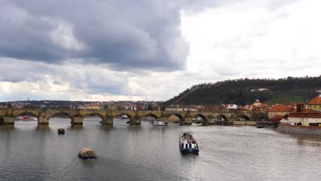 Ferries-En-El-Río-Moldava-Pasando-Por-Debajo-Del-Puente-De-Carlos,-Praga,-República-Checa